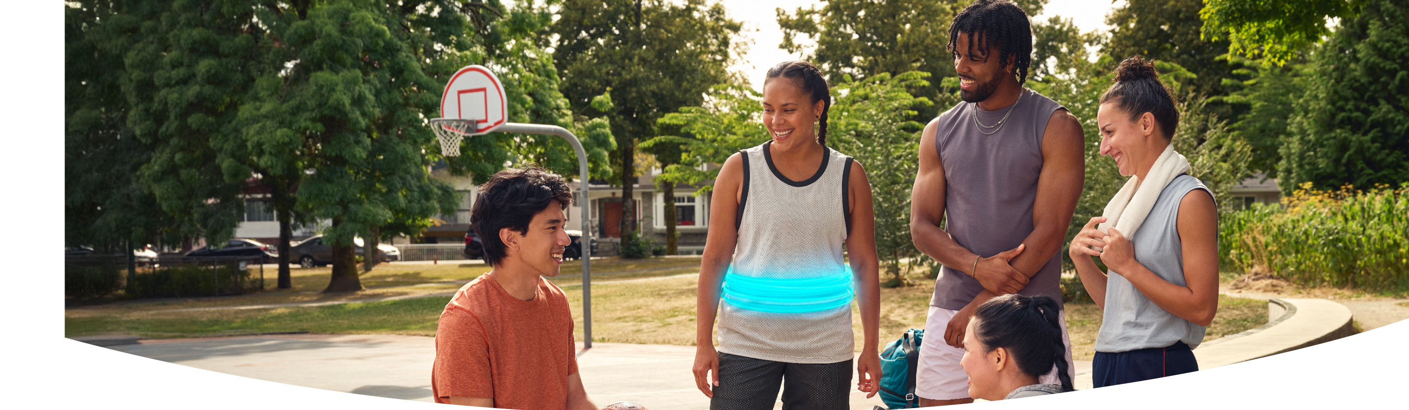 Two women and a man smiling together outside, one with a blue ring around her stomach