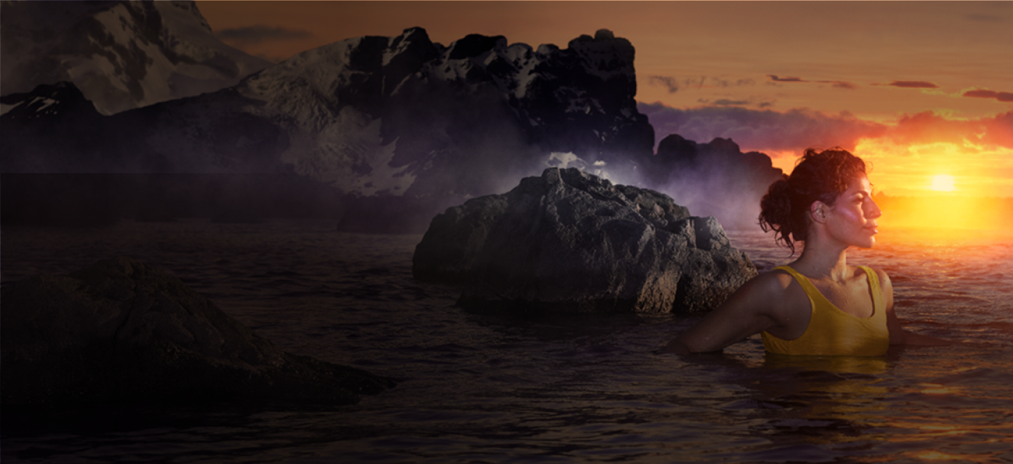 A woman in a yellow swimsuit swimming in a natural hot spring at sunset