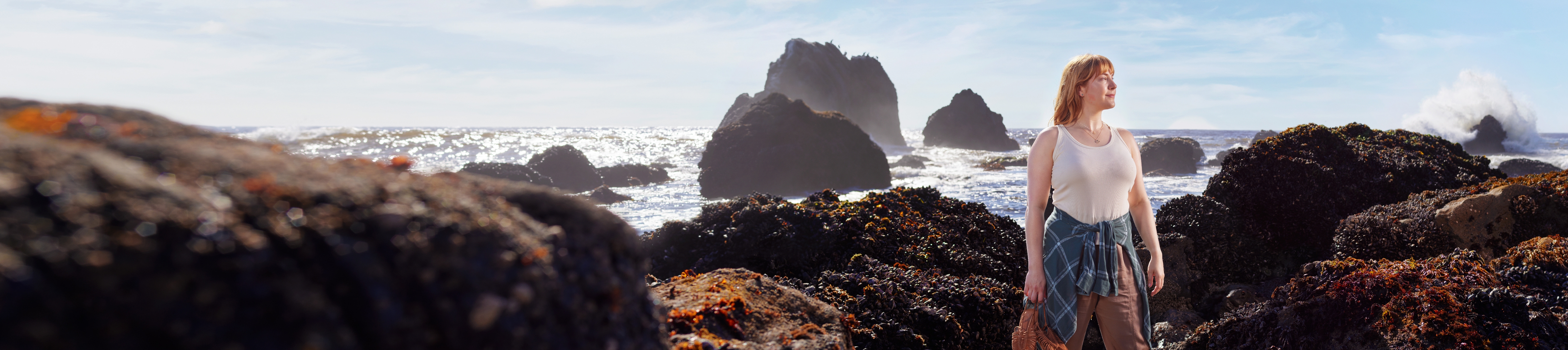 Adult woman standing in front of rocks on the beach