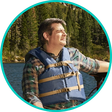 Man in a life vest on a lake with woods in the background