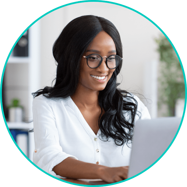 Woman in white shirt and in white room looking down at laptop