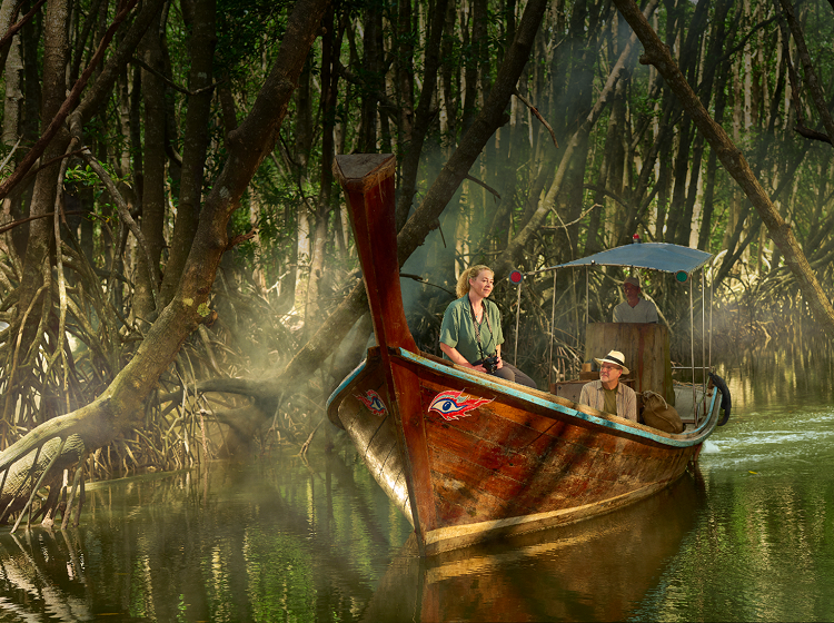 Woman and man sitting in a wooden boat floating through a jungle
