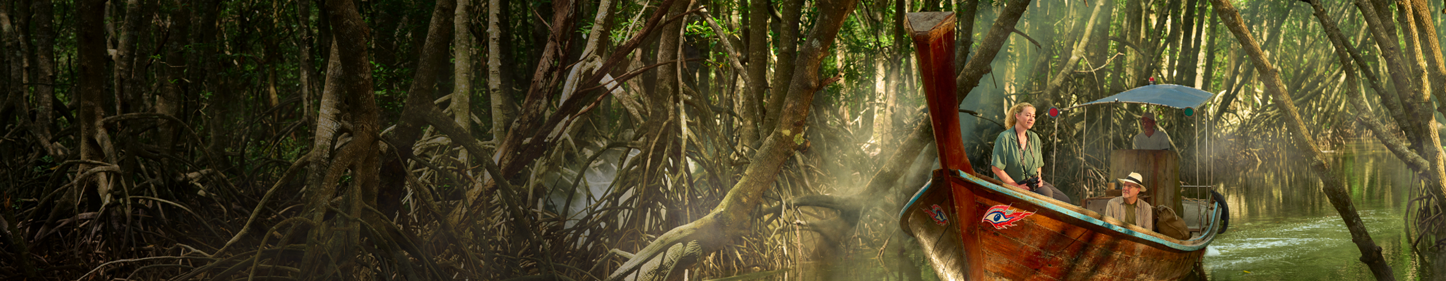Woman and man sitting in a wooden boat floating through a jungle
