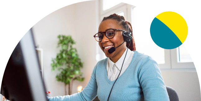 Support specialist smiling while wearing a headset at a computer