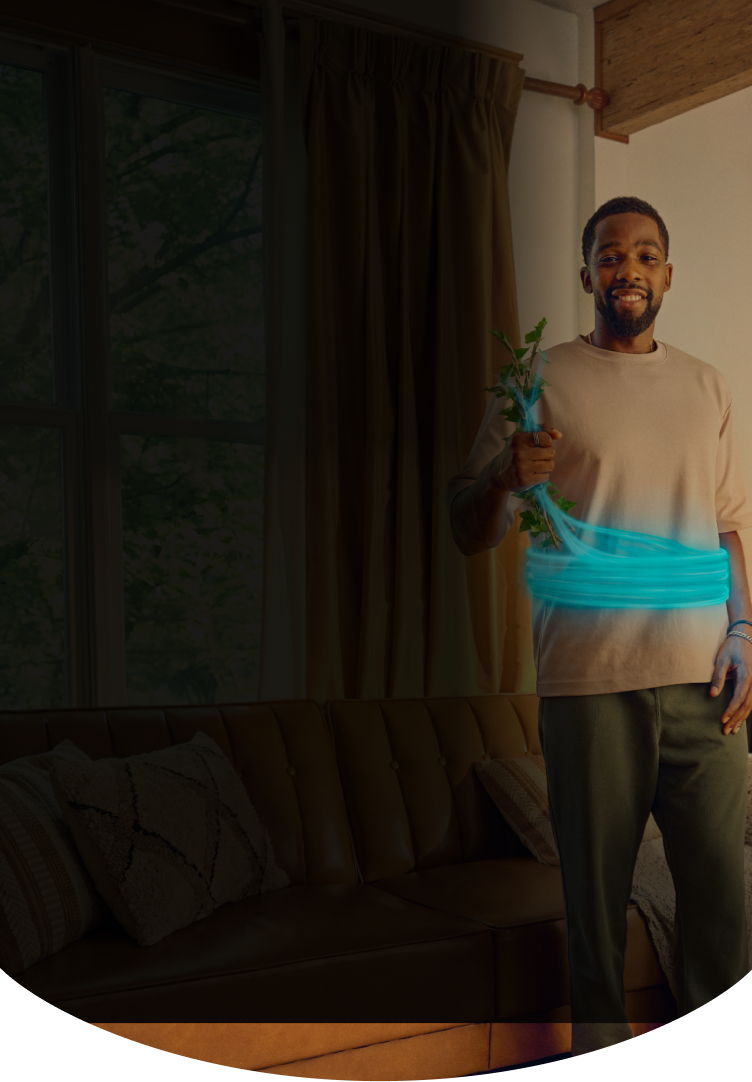 Man smiling while holding up a plant with a blue ring around his stomach
